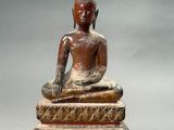 statue of a seated buddha sitting on a stone block