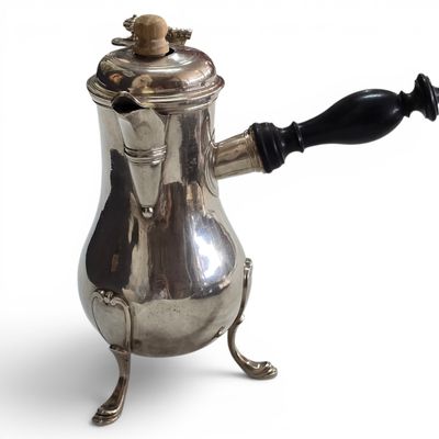 a silver coffee pot with a black handle on a white background