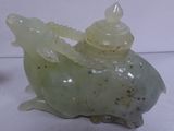 a green dragon figurine sitting on a white surface
