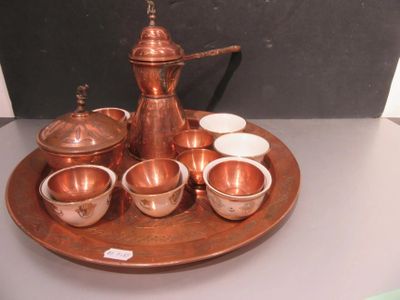 a copper tea set on a tray with cups and saucers