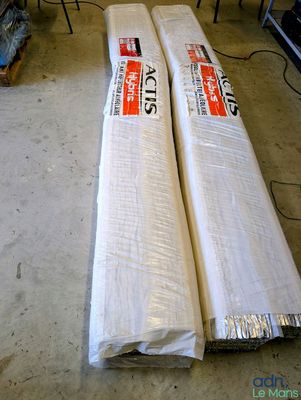 deux rouleaux de tissu blanc posés par terre dans une pièce