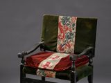 une vieille chaise sur laquelle est posé un coussin rouge et vert