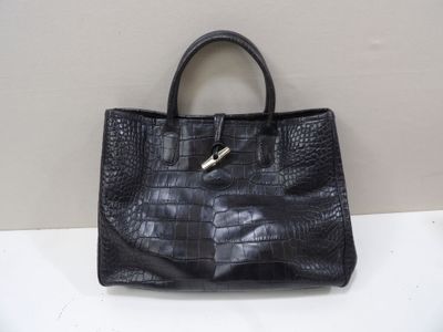 black leather handbag with a metal handle sitting on a white surface