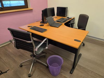 un bureau avec deux ordinateurs et un seau posé par terre