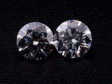two round cut diamonds on a black surface