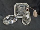 two clear glass bottles and a silver plate with a cat on it