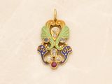 a gold pendant with a bird and a flower design on it