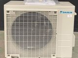 an air conditioner sitting on top of a cement floor next to a black wall