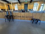 un bar avec des tabourets devant et une enseigne indiquant « Cave de la Cité »
