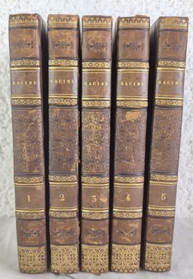 six antique books lined up in a row on top of a table