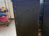 two black refrigerators sitting on a pallet in a room