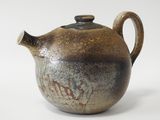 a brown teapot with a black lid on a white surface