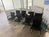 plusieurs chaises noires dans une pièce où se trouve un tableau blanc accroché au mur