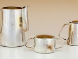 trois pichets en argent et une coupe posés sur une table