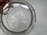 a person holding a clear glass bowl with a starburst design on it