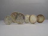 six different types of coins are arranged in a row on a white surface