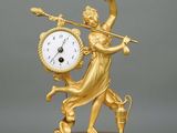an image of a gold clock with a woman holding a sword