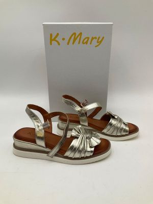 une paire de sandales argentées avec une boîte de K Mary