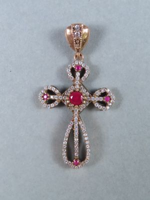 a close up of a diamond cross pendant on a white surface