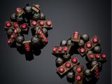 two pairs of earrings with pink stones on a black surface