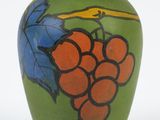 a green vase with a bunch of grapes painted on it