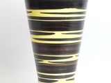 black and yellow striped vase sitting on a white surface