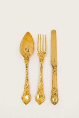 gold plated cutler set with a knife, fork and spoon on a white surface