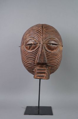 gros plan d'un masque en bois sur un support sur fond blanc