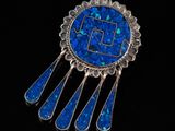 un gros plan sur une broche bleue ornée d'incrustations d'argent