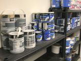 many cans of paint sitting on a shelf in a room