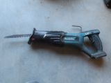 a cordless saw on the floor next to a pair of shoes