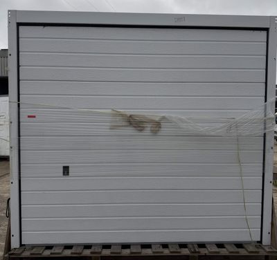 a picture of a white garage door on a pallet in a parking lot