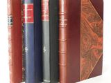 several books are lined up in a row on a white surface