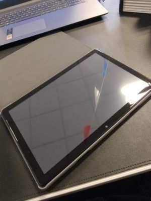 une tablette posée sur un bureau, à côté d'un ordinateur portable