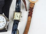 three watches and a watch strap on a white table
