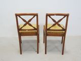 two wooden chairs with a yellow cushion on them in a room