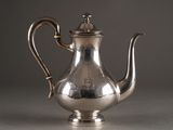 an antique silver tea pot with a handle on a table
