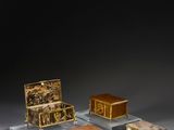 three small boxes and a small chest on display on a table