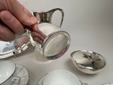 a person pouring sugar into a silver tea pot
