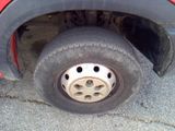 a red car with a flat tire that has holes in it