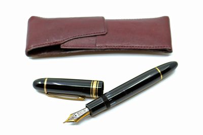 un stylo et un étui en cuir posés sur une surface blanche