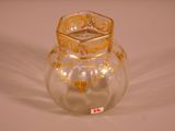 a glass vase that has a gold decoration on it