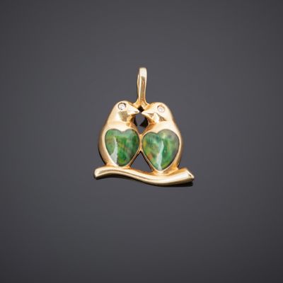 un pendentif en or représentant deux chats verts sur une branche