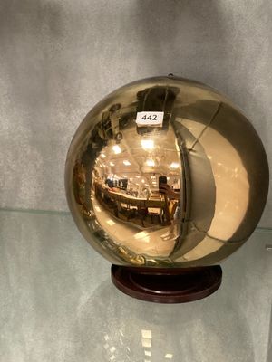 une boule de verre brillante posée sur un socle en bois, sur une table en verre