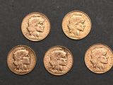 four gold sovereigns of different sizes and shapes on a black surface