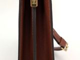 brown leather handbag with gold hardware and strap on a white background