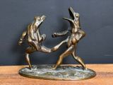 bronze statue of two women fighting each other on a wooden table