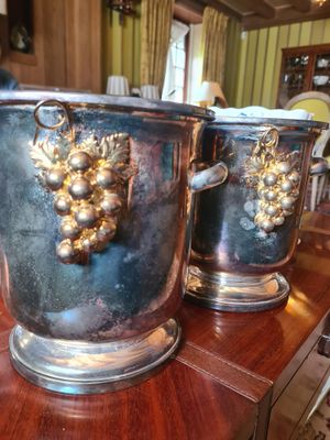 trois vases en argent ornés de raisins, posés sur une table