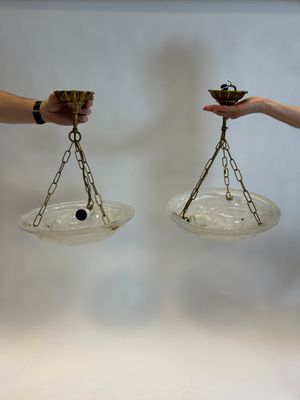 two people holding a pair of glass bowls with chains