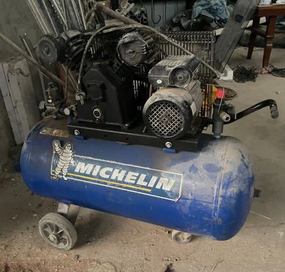 un compresseur d'air bleu posé sur un chariot dans un garage